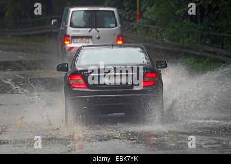 Auto passando attraverso parzialmente allagato road, Germania Foto Stock