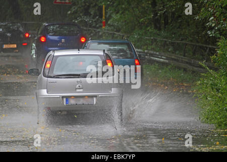 Auto passando attraverso parzialmente allagato road, Germania Foto Stock