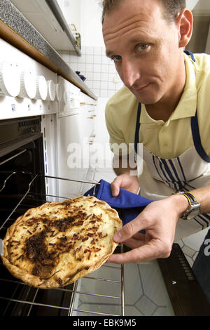 Uomo di ottenere in modo scettico un olocausto Tarte flambe fuori il forno Foto Stock