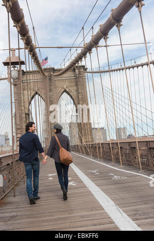 Stati Uniti d'America, nello Stato di New York, New York, Brooklyn, giovane tenendo le mani e camminando sul Ponte di Brooklyn Foto Stock