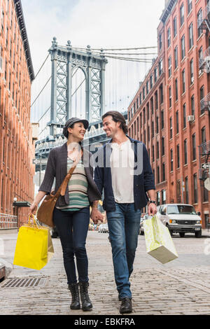 Stati Uniti d'America, nello Stato di New York, New York, Brooklyn, giovane camminando sulla strada, il Ponte di Brooklyn in background Foto Stock