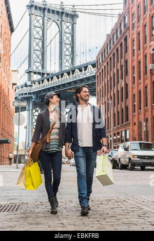 Stati Uniti d'America, nello Stato di New York, New York, Brooklyn, giovane camminando sulla strada, il Ponte di Brooklyn in background Foto Stock