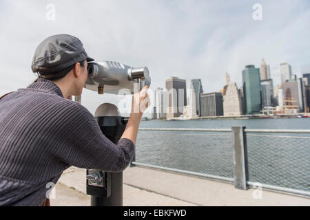 Stati Uniti d'America, nello Stato di New York, New York, Brooklyn, Donna guardando cityscape attraverso la gettoniera binocolo Foto Stock