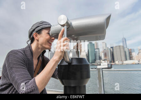 Stati Uniti d'America, nello Stato di New York, New York, Brooklyn, Donna guardando attraverso la gettoniera binocolo Foto Stock