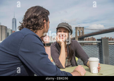 Stati Uniti d'America, nello Stato di New York, New York, Brooklyn, felice coppia seduta e di discutere con il paesaggio urbano in background Foto Stock