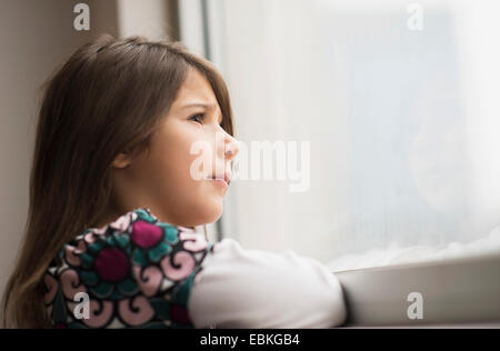 La ragazza (6-7) guardando fuori della finestra Foto Stock