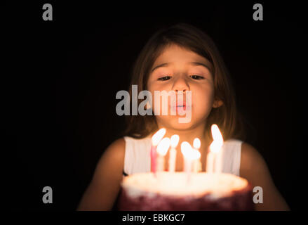 Ritratto di ragazza (6-7) che spegne le candeline sulla torta del compleanno Foto Stock