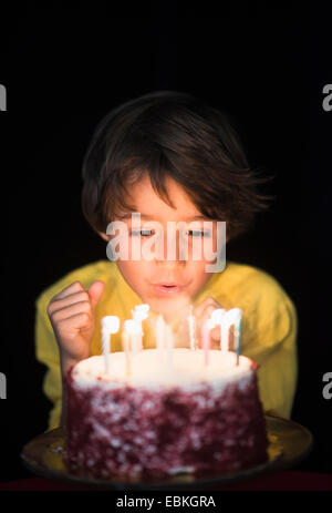 Ritratto di ragazzo (6-7) che spegne le candeline sulla torta del compleanno Foto Stock