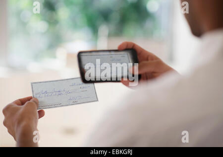 L'uomo prendendo foto del controllo bancario con un telefono cellulare Foto Stock