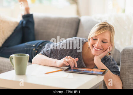 Donna sdraiata sul divano con i tablet pc Foto Stock