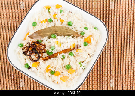 Primo piano vista dalla cima della verdura deliziosa pulao guarnite con foglie di alloro, il bastoncino di cannella e cipolla fritti. Foto Stock