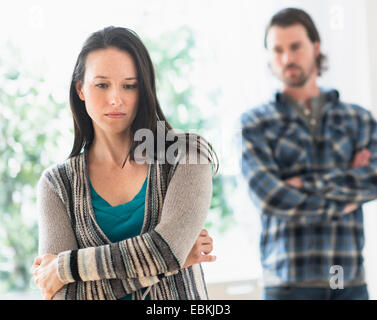 Triste donna con le braccia incrociate, uomo in background Foto Stock