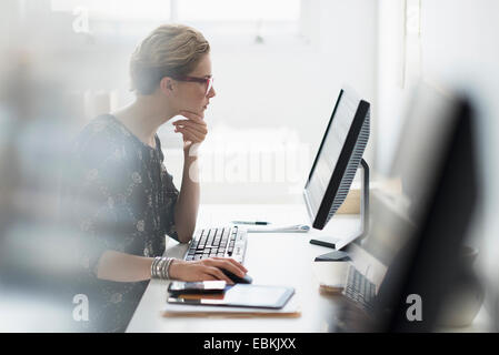 Vista laterale del business donna lavora sul PC desktop in ufficio Foto Stock