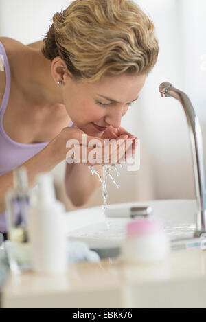 Giovane donna faccia di lavaggio nella stanza da bagno Foto Stock