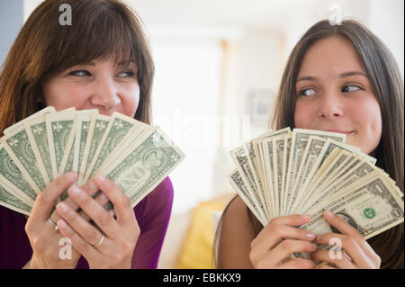 Ragazza adolescente (14-15) e sua mamma tenendo le fatture del dollaro Foto Stock