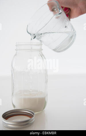 Donna mescolare il latte con acqua Foto Stock