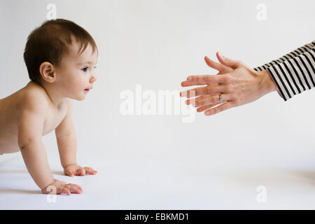 Madre incoraggiando la figlia (12-17 mesi) a piedi Foto Stock