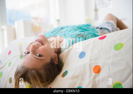La ragazza (12-13) sdraiato sul letto sorridente Foto Stock
