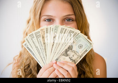 La ragazza (12-13) che fissano la ventola del denaro contro il suo volto Foto Stock