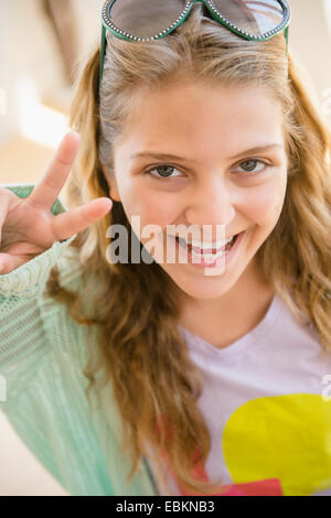 Ritratto di sorridente ragazza adolescente (12-13) che mostra un segno di pace Foto Stock