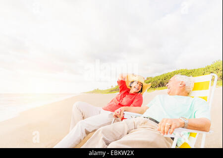 Stati Uniti d'America, Florida, Giove, vista del giovane seduto in sedie a sdraio sulla spiaggia e ridere Foto Stock