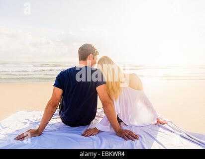 Stati Uniti d'America, Florida, Giove, vista posteriore della coppia giovane seduto su una coperta sulla spiaggia sabbiosa, guardando il mare Foto Stock
