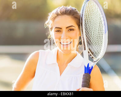 Ritratto di sorridente giovane donna holding racchetta da tennis Foto Stock