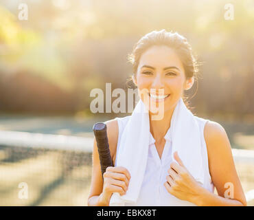 Ritratto di sorridente giovane donna con asciugamano e racchetta da tennis Foto Stock