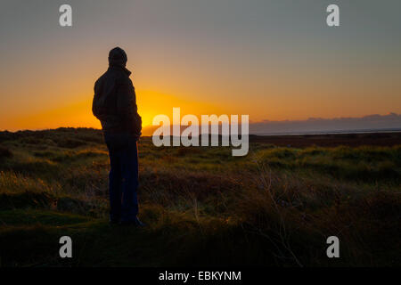 Silhouette al tramonto a Southport, Merseyside, Regno Unito. 2 dicembre 2014. Uomo dalle silhouette. Regno Unito tempo come visto alla Riserva Naturale Nazionale delle dune di sabbia di Ainsdale (NNR). Una notte fredda e limpida in vista con temperature inferiori allo zero previste per la regione costiera occidentale dell'Inghilterra settentrionale, quando il sole tramonta sul Mare d'Irlanda. Foto Stock