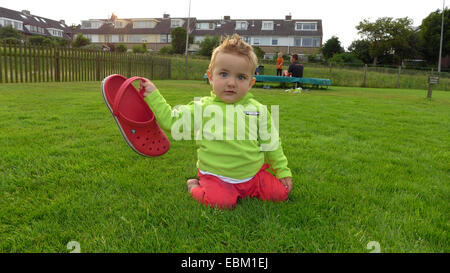 Little Boy kneeing in un prato e giocare con una gomma intasare, Germania Foto Stock