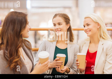 Giovani donne con le borse della spesa e caffè in mall Foto Stock