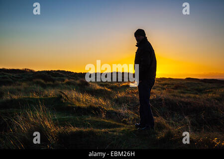 Southport, Merseyside, Regno Unito. 2 dicembre, 2014. Silhouette uomo. Regno Unito Meteo come si vede a Ainsdale dune di sabbia riserva naturale nazionale (NNR). Una chiara notte fredda in prospettiva con temperature sotto zero previsioni per il west regione costiera del Nord Inghilterra come il sole tramonta sul mare d'Irlanda. Foto Stock