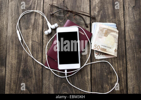 Preparazione per il viaggio, telefono cellulare, denaro, passaporto sul tavolo di legno Foto Stock