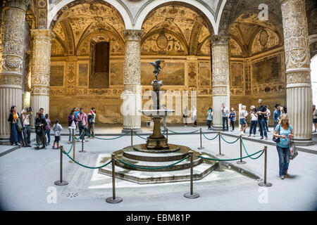 Visitatori stand in un timore reverenziale per il romanico splendore del Palazzo Vecchio ingresso corte con affreschi rinascimentali di Giorgio Vasari Foto Stock