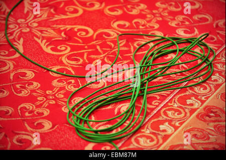 Dettaglio delle riprese con una verde televisione tv via cavo avvolto su un tappeto rosso Foto Stock