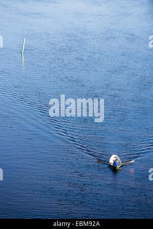 Vista aerea di un uomo che rema una piccola barca a remi in vetroresina / skiff / dinghy , Finlandia Foto Stock