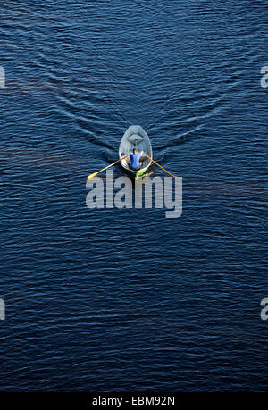 Vista aerea di un uomo che rema una piccola barca a remi in vetroresina / skiff / dinghy , Finlandia Foto Stock