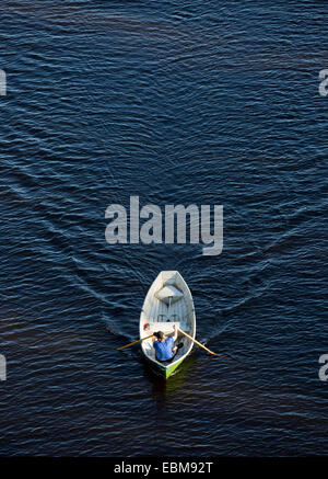 Vista aerea di un uomo che rema una piccola barca a remi in vetroresina / skiff / dinghy , Finlandia Foto Stock