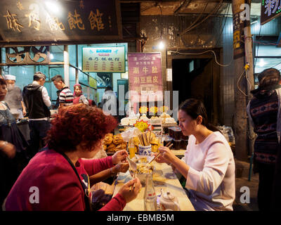 Persone mangiare con bacchette per le strade del quartiere musulmano di Xian, Cina Foto Stock