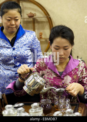 Giovane donna versando il tè durante una tradizionale cerimonia del tè cinese Foto Stock