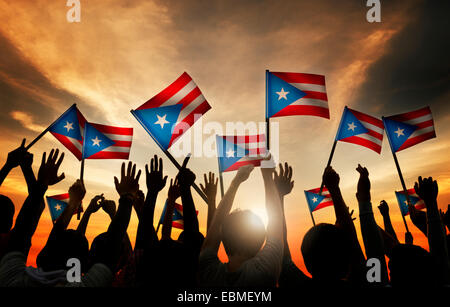 Gruppo di persone sventola Bandiera di Puerto Rico in retro illuminato Foto Stock