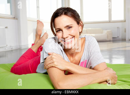 Giovane donna in abiti casual giacente sul bean bag in un loft, Germania Foto Stock