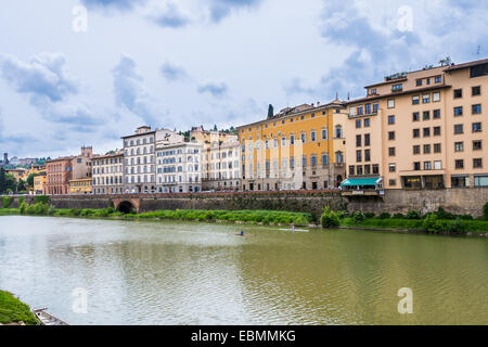 Scorcio del fiume Arno a Ponte Vecchio a Firenze con case tipiche e canoe in acqua in un giorno nuvoloso Foto Stock