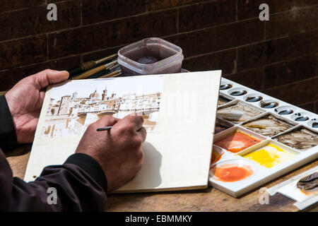 Dettaglio delle mani e degli attrezzi da lavoro di un artista di strada che dipinge il Ponte Vecchio a Firenze, colori caldi Foto Stock