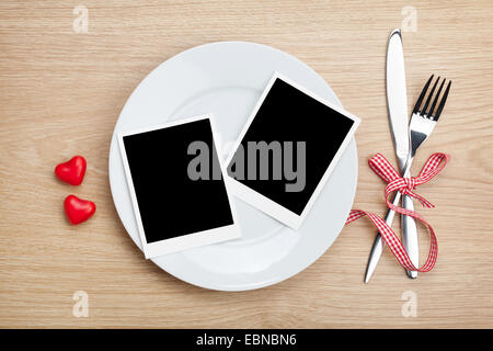 Il giorno di San Valentino blank foto telai su piastra e posate sul tavolo di legno sfondo Foto Stock