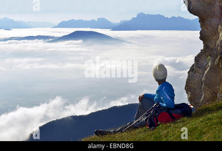 Femmina degli escursionisti di montagna seduto su una montagna e godendo la vista al di sopra del cloud, Francia, Deux Soeurs, Vercors Parco Nazionale Foto Stock