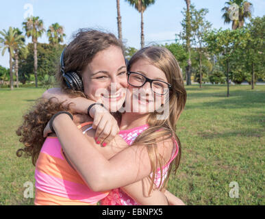 Due ragazza goofing intorno e leggere su un prato in posizione di parcheggio Foto Stock