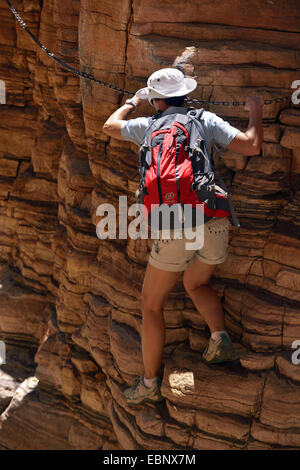 Femmina wanderer arrampicata in corrispondenza di una parete di roccia nella Naukluftberge montagne, Namibia, Namib Naukluft National Park Foto Stock