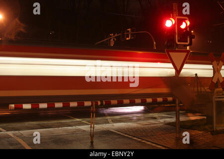 Treno che passa un attraversamento ferroviario di notte, in Germania, in Renania settentrionale-Vestfalia Foto Stock