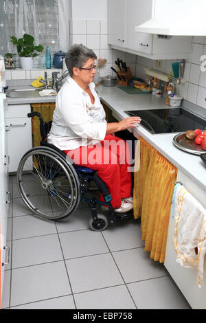 Sedia a rotelle utente in un accessibile ai disabili cucina Foto Stock